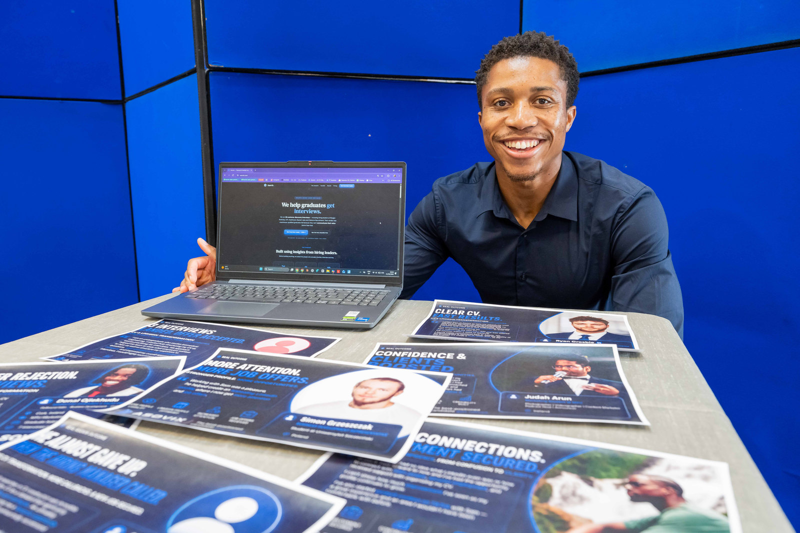 Samuel Adu, founder of Asovix, at a table with the Asovix site open on his laptop and printed client result cards spread in front of him